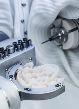 Eine Nahaufnahme einer CAD/CAM Dentalfräse, die in einem Labor ein künstliches Gebiss formt.